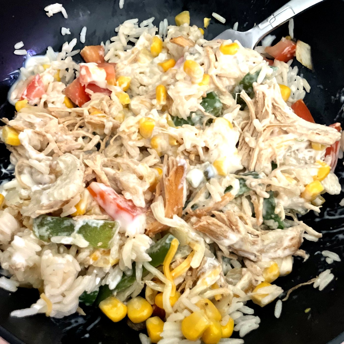 The burrito bowl stirred together with rice, chicken, corn, peppers and tomato